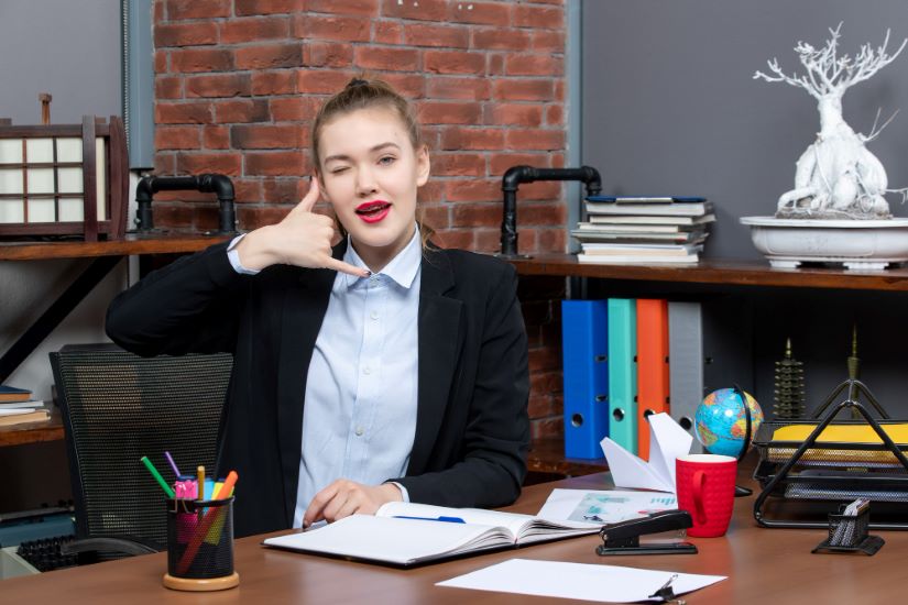 Top view of confident young female sitting at a table and holding the documen