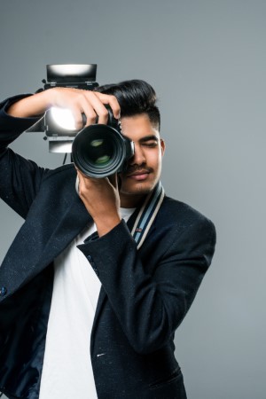 Professional indian young photographer taking photos in a studio with light